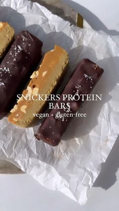 three chocolate covered desserts sitting on top of a piece of wax paper with the words, snickkers protein bars vegan + glutter - free