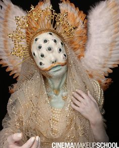 a woman wearing an elaborate mask with white feathers on her head and gold trimmings