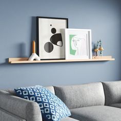 a living room with blue walls and a gray couch in front of a framed art piece