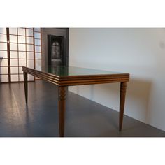 a wooden table sitting on top of a floor next to a white wall and window