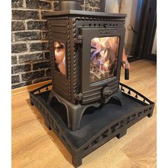 a wood burning stove sitting on top of a wooden floor next to a brick wall