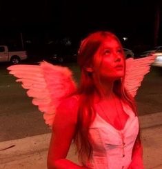 a woman with pink wings standing on the sidewalk