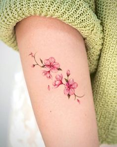 a woman's arm with pink flowers tattooed on the left side of her body