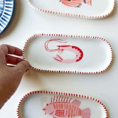 three plates with fish painted on them are being held by a person's hand