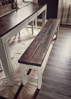 a wooden bench sitting next to a white table on top of a hard wood floor