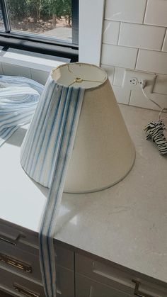 a lamp shade sitting on top of a counter next to a window