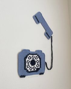 a blue crocheted phone is hanging on the wall