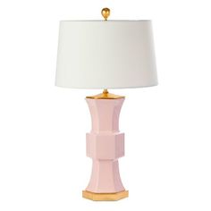 a pink table lamp with a white shade on the top and gold trim around the base