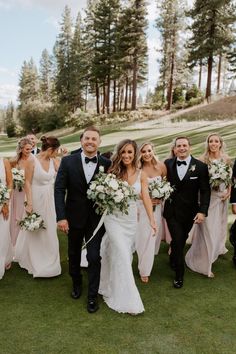 a bride and groom with their bridal party on the golf course at this wedding