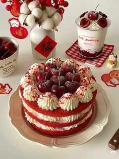 a red velvet cake with cherries and whipped cream on top, surrounded by cherry decorations