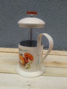 a coffee cup with a lid and handle is sitting on a wooden table next to a wall