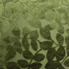 the shadow of leaves is cast on a green fabric with black spots and lines in it