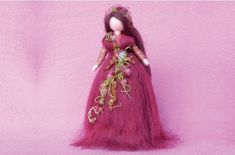 the doll is wearing a long pink dress with flowers on it's head and hair