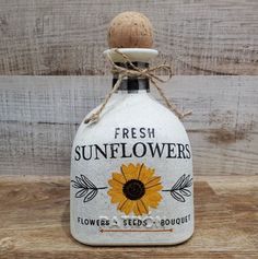 a bottle with a sunflower on it sitting on a wooden table