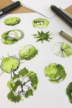 some green inks are sitting on top of a piece of paper with watercolor pencils