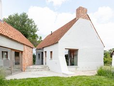 a white house with red tiled roof and brick chimneys