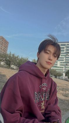 a young man sitting on top of a bench next to a tall building and looking at the camera