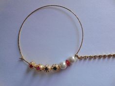 a close up of a bracelet on a white surface with gold chains and beads hanging from it