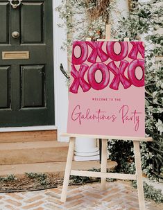 a pink sign sitting on top of a wooden easel in front of a door