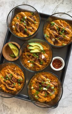 six bowls filled with food sitting on top of a tray next to an avocado