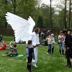 a woman dressed as an angel standing in the grass