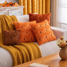 a living room filled with lots of pillows on top of a white couch next to a window