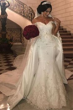 a woman in a wedding dress standing next to a stair case and holding a bouquet