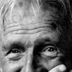 black and white photograph of an older man with his hands on his face, looking at the camera