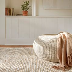 a large white ottoman sitting on top of a wooden floor next to a potted plant