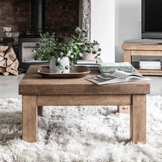 a living room with a coffee table, television and fire place in the background on a shaggy rug