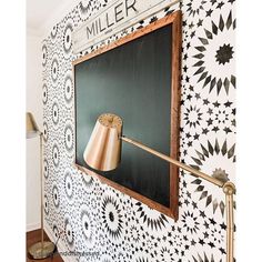 a black and white wall with a copper lamp on the chalkboard that says miller