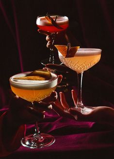 three different types of cocktails being held up in front of each other with their hands