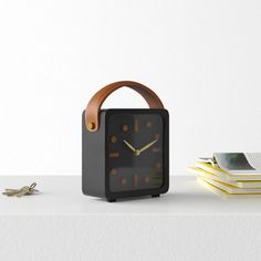 a black clock sitting on top of a table next to a stack of books and a pair of scissors