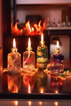 four candles are lit on a table in front of a fireplace