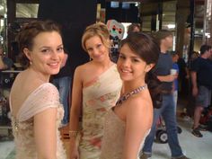 three beautiful young women standing next to each other in front of a cameraman's booth