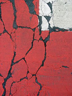 a red and white wall with cracks in it