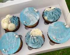 four cupcakes with blue frosting in a box