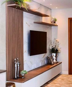 a flat screen tv mounted to the side of a wall next to a vase with flowers