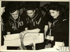 an old black and white photo of people in sailor uniforms looking at something on a table