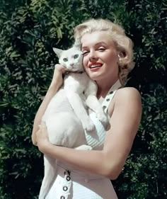 a woman holding a white cat in her arms