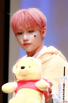 a person with pink hair holding a teddy bear