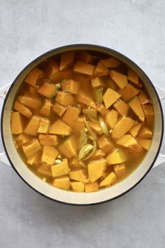 a pot filled with food sitting on top of a white counter next to a spoon