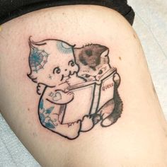 a tattoo on the leg of a person with a cat holding a book in it's lap