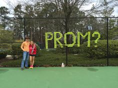 two people standing on a tennis court with the word prom spelled in neon green letters