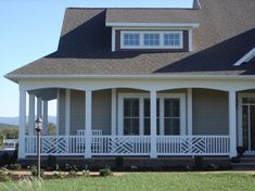 a large gray house with white railings on the front porch and side entry door