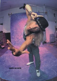 a man with long hair doing a handstand in front of a purple background