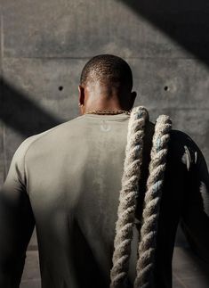 a man with dreadlocks standing in front of a wall and looking at something