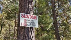 a sign posted on a tree in the woods warning people not to enter slovdomn