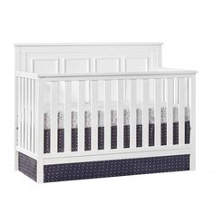 a white crib with blue polka dots on the bottom and side panels, in front of a white background