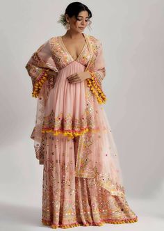 The zohra peplum with sharara with mirror work and pompoms and tassels with detailed hand and machine embroidery is perfect for festive occasions such as weddings, parties and cultural celebrations. Embrace the timeless beauty and elegance of this outfit and make a statement wherever you go. Festive Bollywood Kurta With Tassels, Festive Kurta With Tassels, Festival Kurta With Tassels, Eid Bollywood Kurta With Tassels, Bollywood Style Festive Kurta With Tassels, Anarkali Kurta With Tassels For Navratri, Navratri Anarkali Kurta With Tassels, Traditional Kurta With Tassels For Navratri, Festive Kurta With Tassels And Traditional Drape